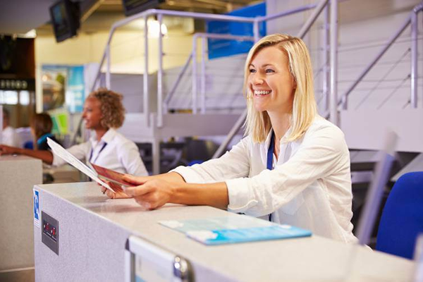 Addetta aeroportuale che assiste passeggeri al banco check-in