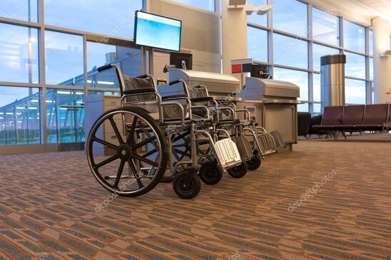 Addetto aeroportuale che assiste un passeggero in sedia a rotelle